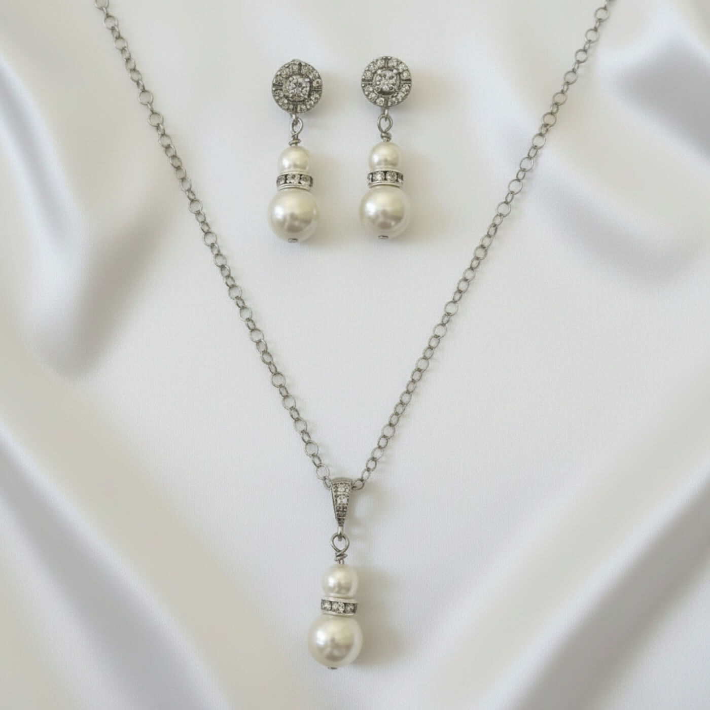 Gold and pearl bridal jewelry set photographed on white satin background