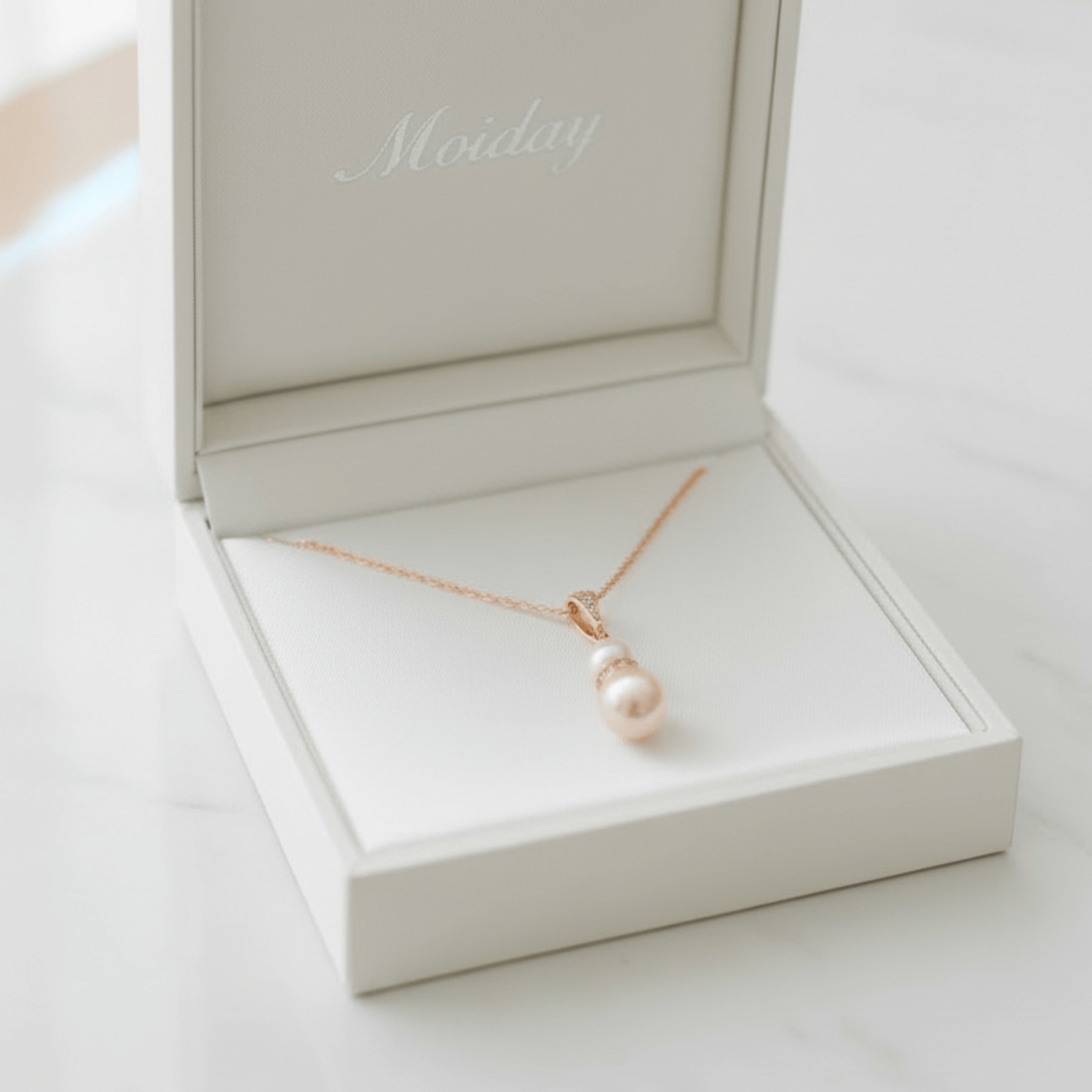 Gold and pearl pendant necklace photographed on white lace fabric