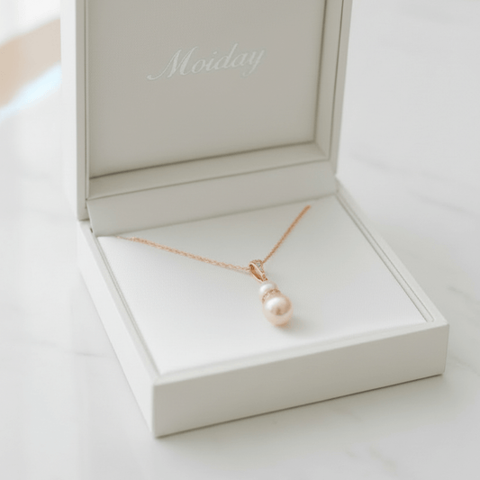 Gold and pearl pendant necklace photographed on white lace fabric