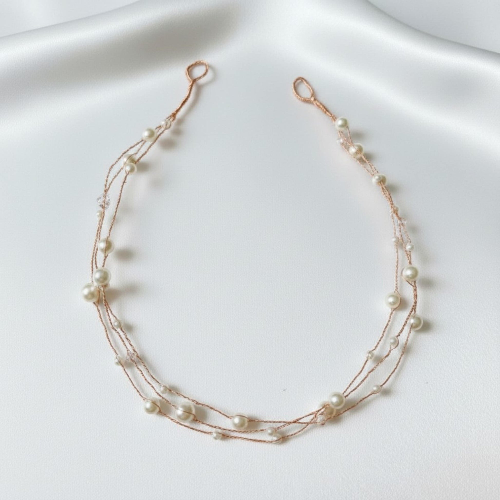 Delicate multi-strand pearl hairvine displayed on white satin.