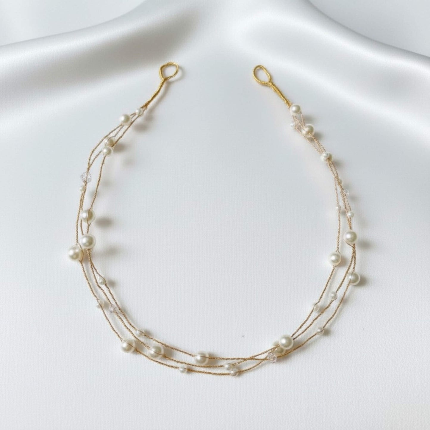 Texture view of the minimal pearl hairvine on a soft satin background.