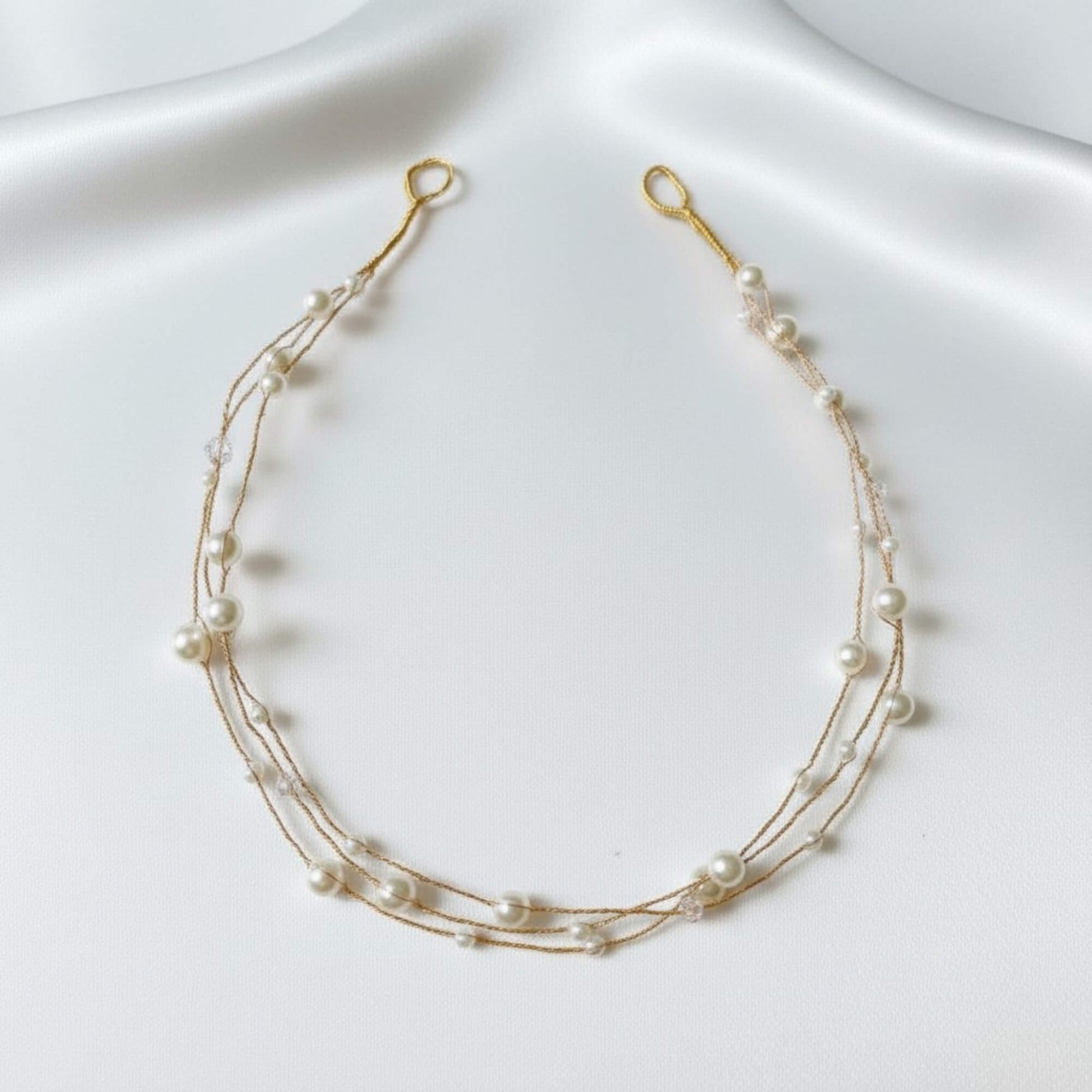 Texture view of the minimal pearl hairvine on a soft satin background.