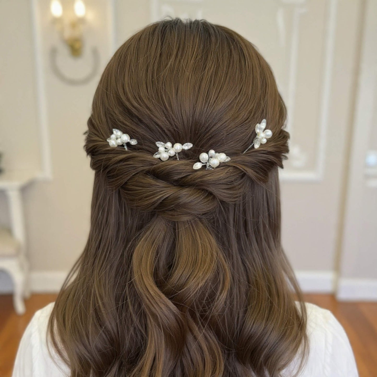 Bridal braided updo from the back with four pearl hair pins placed neatly along the braid, soft luxury bridal style