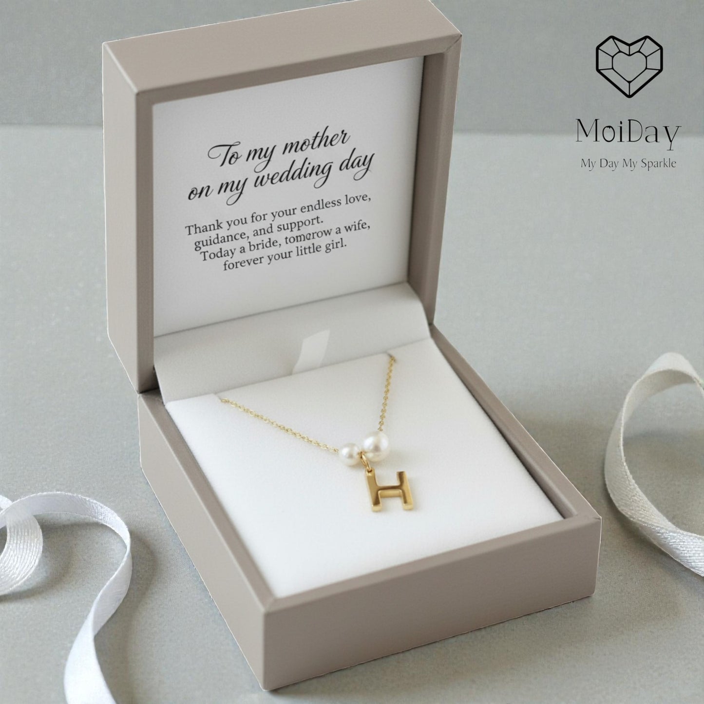 Gold necklace with a letter 'H' in an open gift box with a message, branded 'MoiDay'.