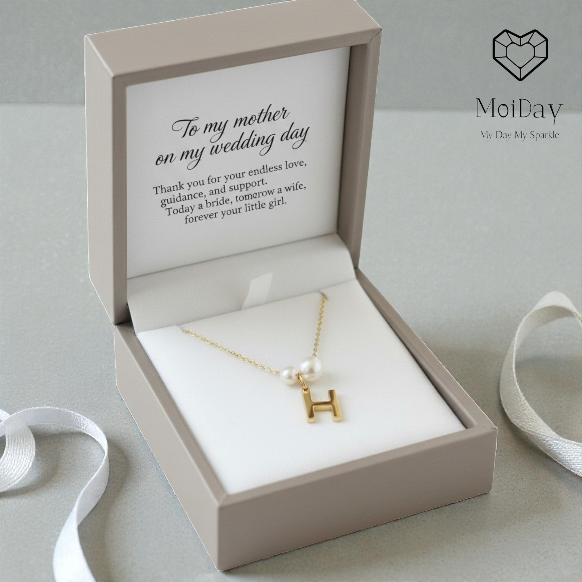 Gold necklace with a letter 'H' in an open gift box with a message, branded 'MoiDay'.