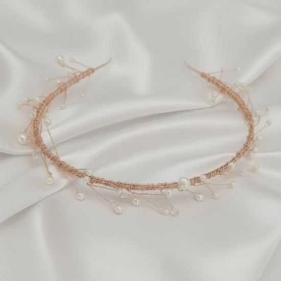 Delicate rose‑gold bridal hairvine with white pearls and clear crystals on white satin.