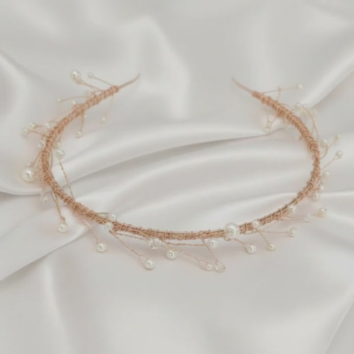 Delicate rose‑gold bridal hairvine with white pearls and clear crystals on white satin.