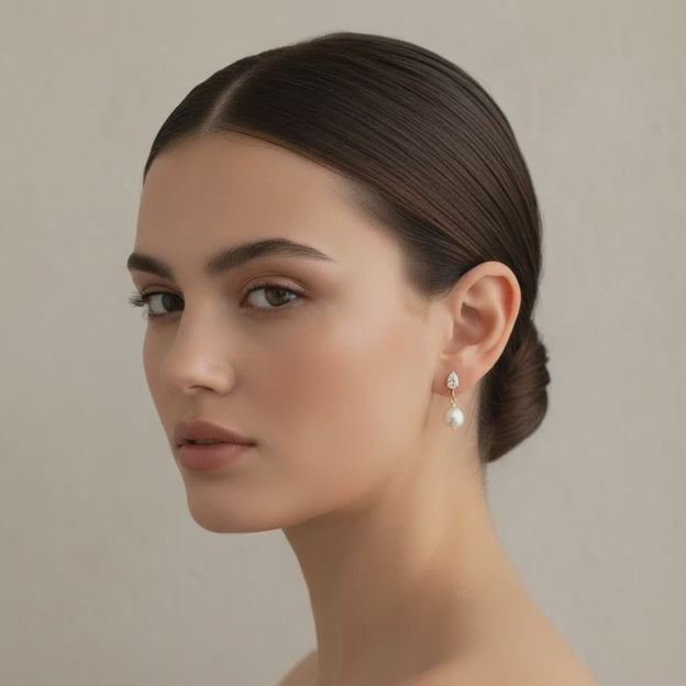 Close-up of bride’s profile showing gold and pearl drop earrings, minimal makeup, soft airy lighting