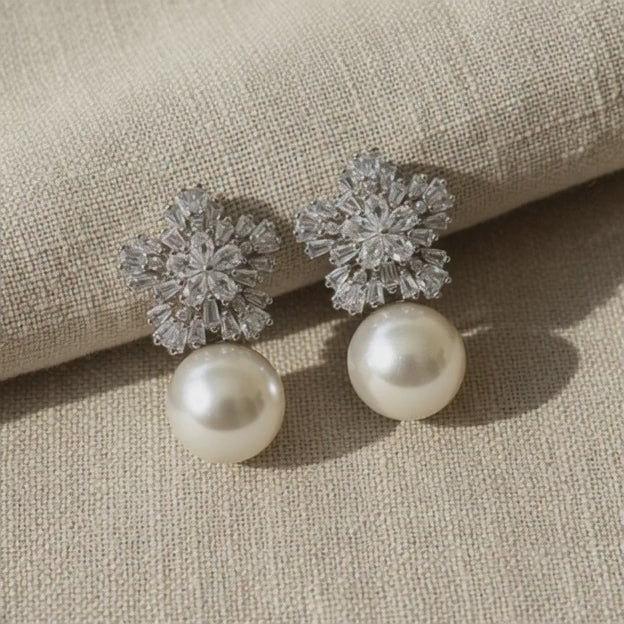 Platinum‑plated pearl and crystal earrings photographed on a clean light surface.