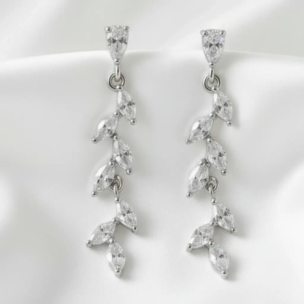 Pair of silver earrings with clear gemstones on a white background
