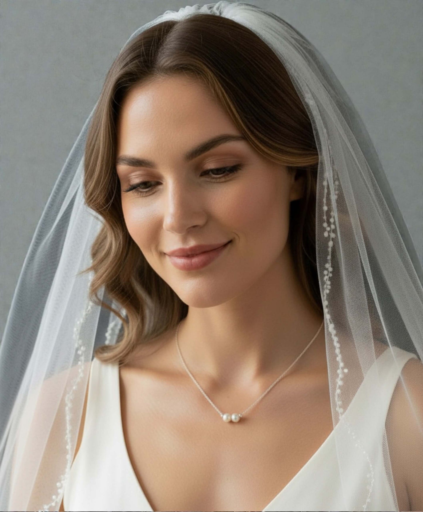 Woman wearing a white wedding dress with a veil against a gray background