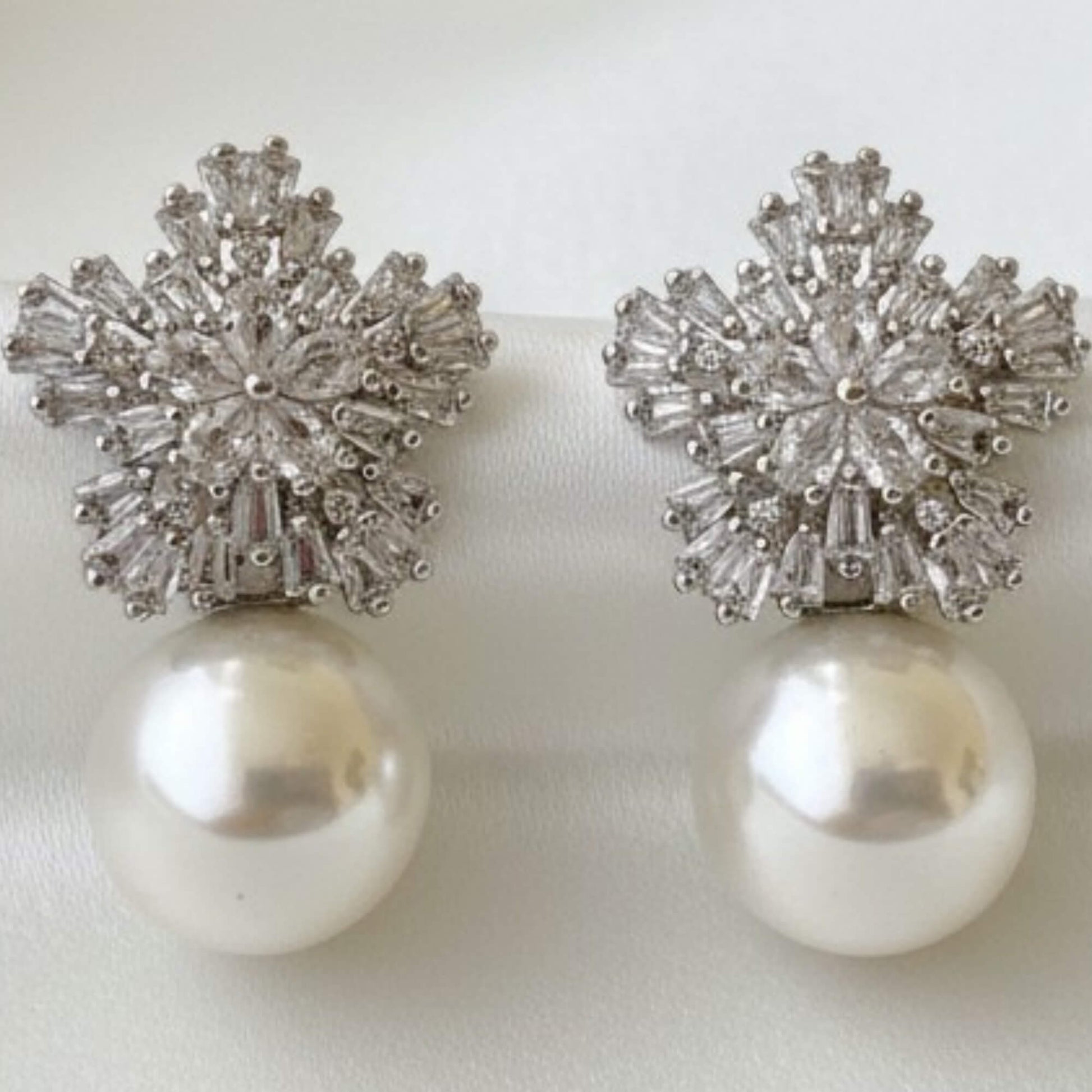 Luxury pearl drop earrings with zirconia accents shown in studio lighting.